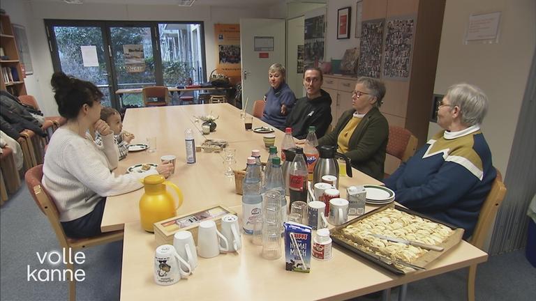 Kleiner Junge malt zusammen mit einer älteren Frau aus dem Mehrgenerationenhaus am Tisch. 