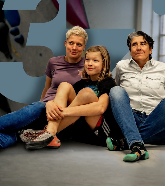 In der Boulderhalle sitzen Judith und Andrea zusammen auf dem Boden. Ihr gemeinsamer Sohn Oskar sitzt in der Mitte.