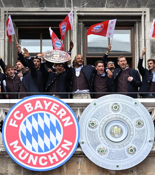 Die Spieler, Trainer und Betreuer vom FC Bayern München jubeln auf dem Rathausbalkon mit der Meisterschale am 17.05.2026 in München.
