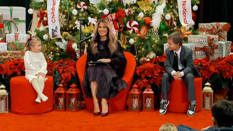 Melania Trump sitzt im Children's National Hospital mit zwei Kindern vor einem Tannenbaum