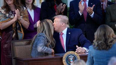 Donald Trump beugt sich zu Melania Trump, um sie zu küssen. Sie dreht den Kopf zur Seite. Sie sitzen im Rosengarten des Weißen Hauses.