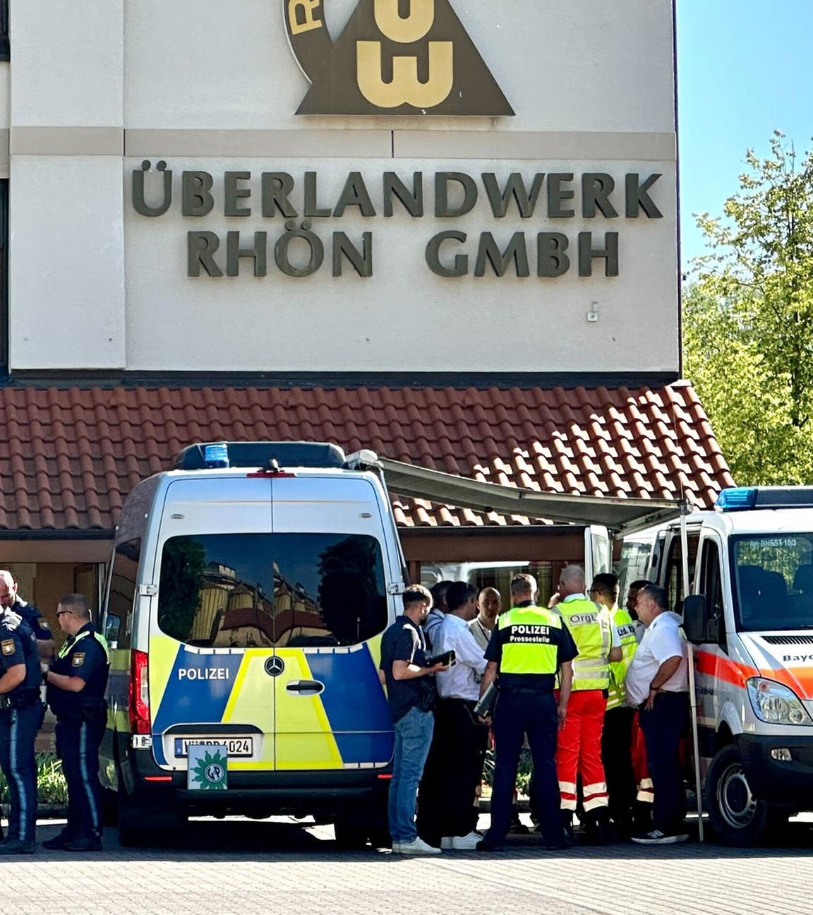 Polizei und Rettungskräfte stehen auf dem Gelände des regionalen Netzbetreibers Überlandwerk Rhön. Ein 21-Jähriger hat am 01.06.2025 in der Firma einen Kollegen getötet und zwei weitere schwer verletzt.