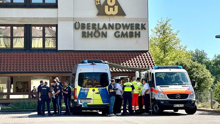 Polizei und Rettungskräfte stehen auf dem Gelände des regionalen Netzbetreibers Überlandwerk Rhön. Ein 21-Jähriger hat am 01.06.2025 in der Firma einen Kollegen getötet und zwei weitere schwer verletzt.