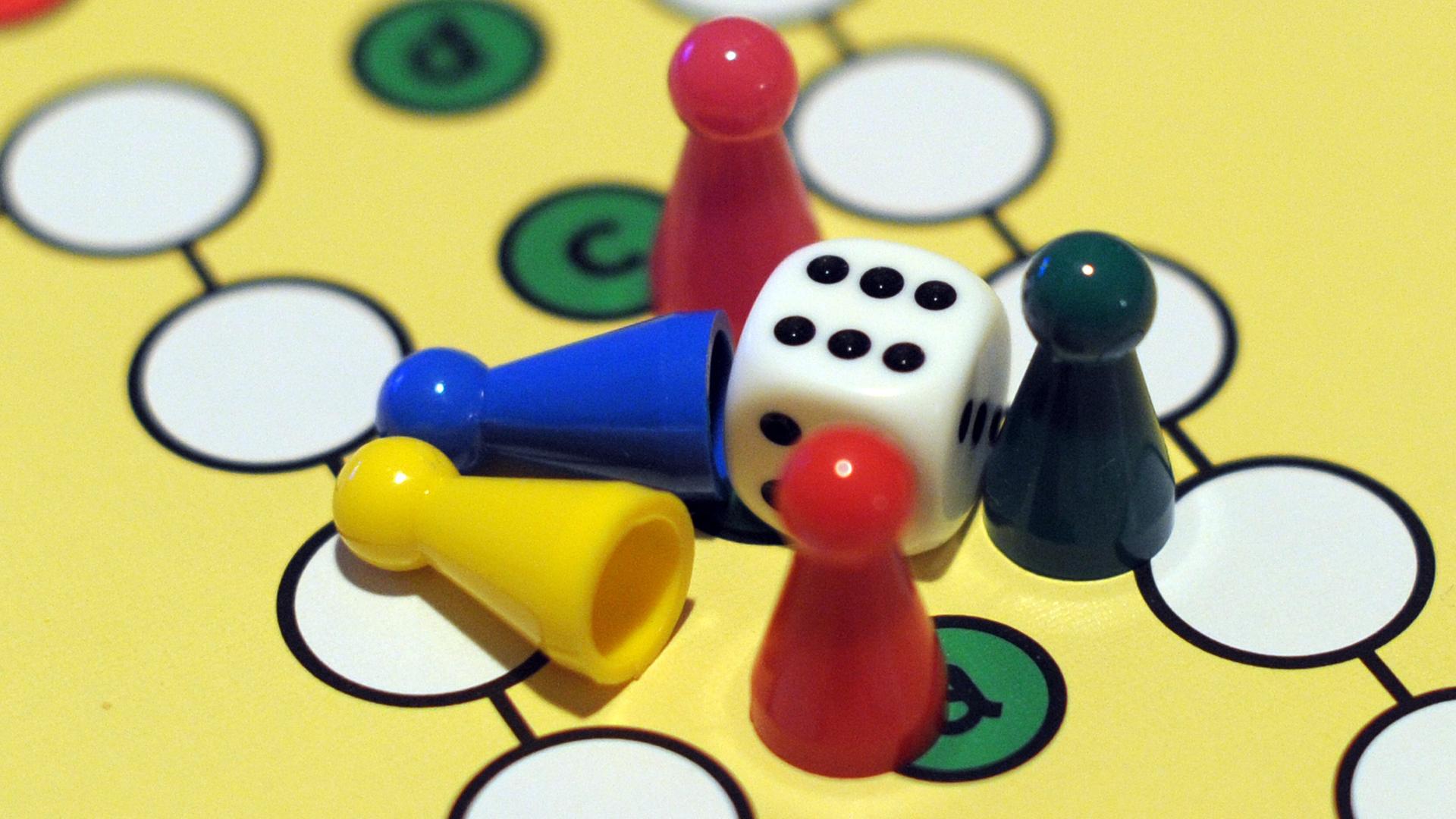 Ein Spielbrett von "Mensch ärgere dich nicht" mit mehreren Figuren und einem Würfel.