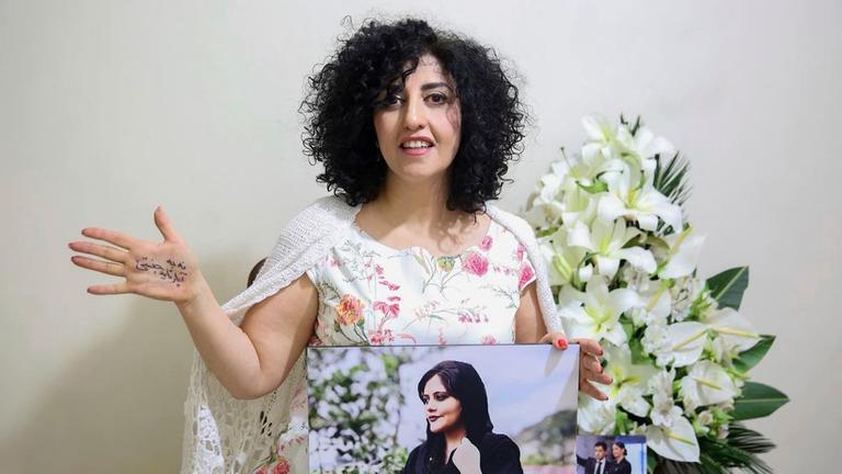 Friedensnobelpreisträgerin Narges Mohammadi mit einem Foto von Jina Mahsa Amini.
