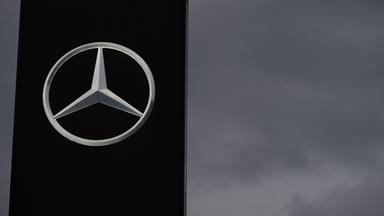Ein Schild mit einem Mercedes-Stern ist vor einem grauen Himmel zu sehen. 