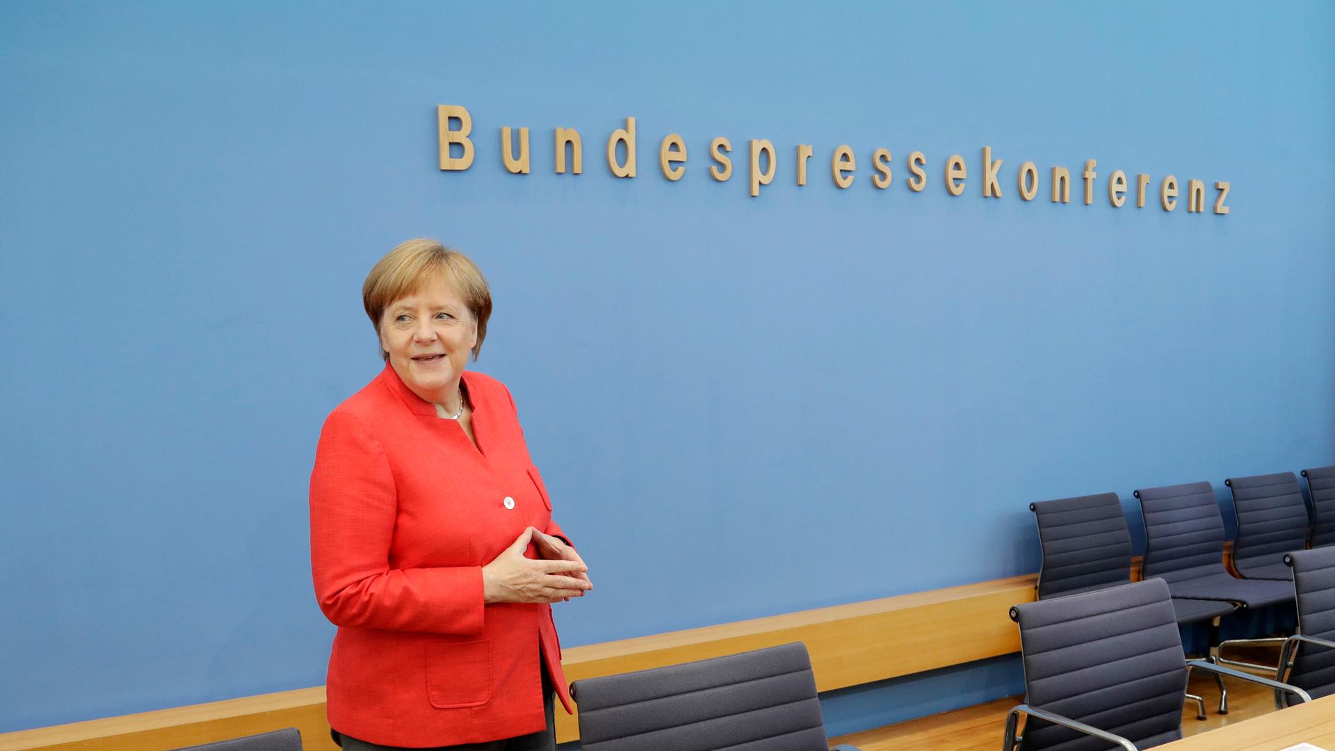 Angela Merkel vor dem Schriftzug der Budnespressekonferenz. Lächelnd, die Hände zur Raute geformt. Aufgenommen am 20.07.2018