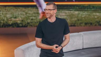 Per Mertesacker steht mit einem schwarzen T-Shirt im ZDF-WM-Studio und blickt lächelnd nach links.