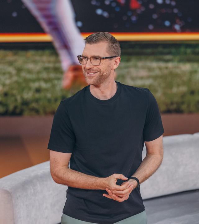 Per Mertesacker steht mit einem schwarzen T-Shirt im ZDF-WM-Studio und blickt lächelnd nach links.