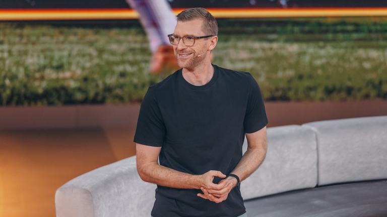 Per Mertesacker steht mit einem schwarzen T-Shirt im ZDF-WM-Studio und blickt lächelnd nach links.