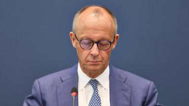 Bundeskanzler Friedrich Merz sitzt und blickt nach unten.