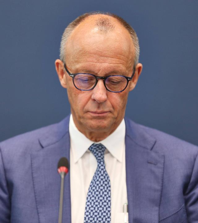 Bundeskanzler Friedrich Merz sitzt und blickt nach unten.