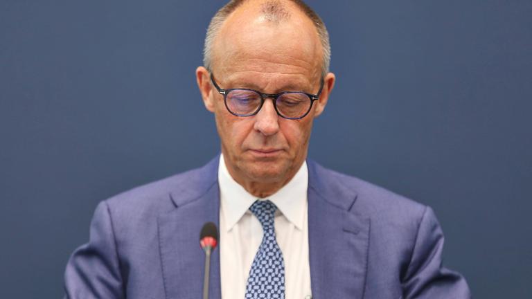 Bundeskanzler Friedrich Merz sitzt und blickt nach unten.