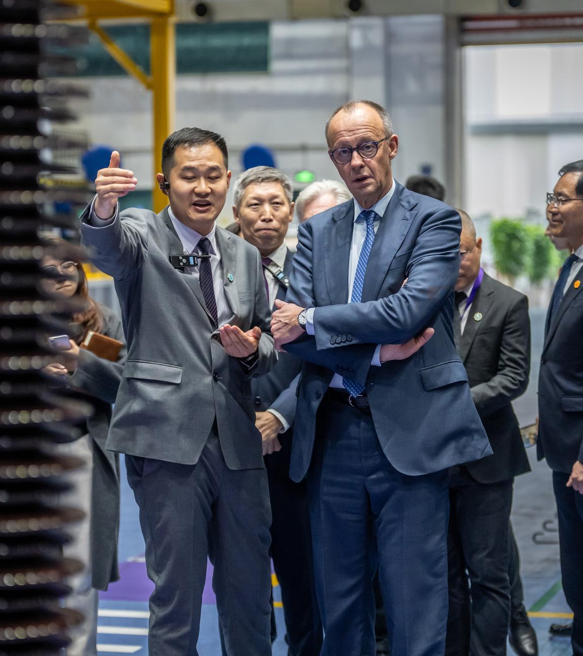 China, Hangzhou: Bundeskanzler Friedrich Merz (CDU) besucht die Firma Siemens Energy und wird von ZUang Wei, Siemens Energy China, Betriebsleiter, durch die Produktionshallen geführt.