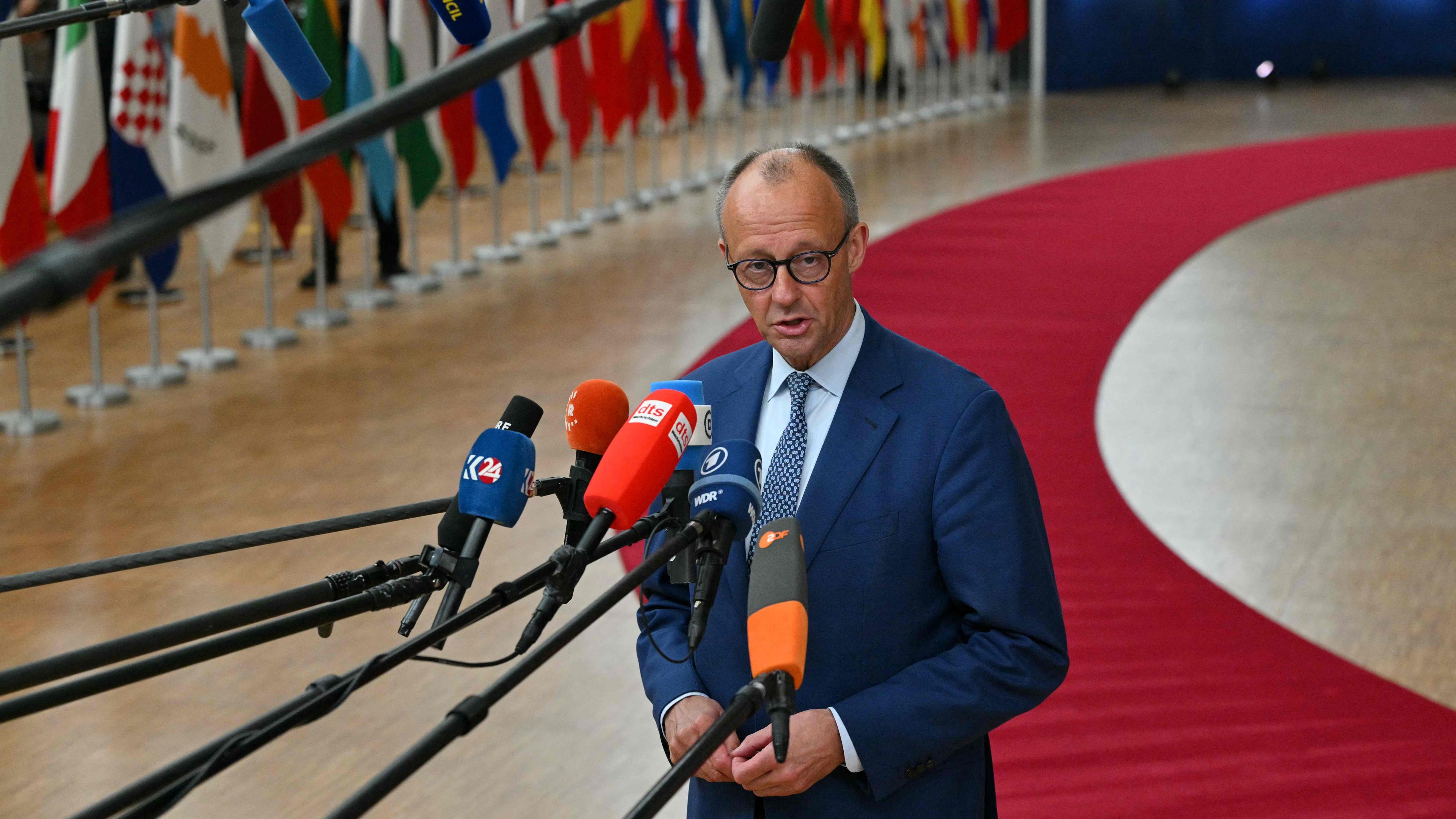 Merz spricht zu Presse, Mikrofone werden ihm entgegengestreckt