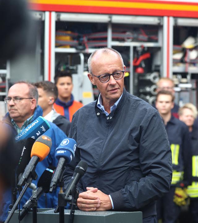 Bundeskanzler Friedrich Merz (M, CDU) spricht bei einem Pressestatement im Hürtgenwald-Gey, links daneben Ralf Nolten (CDU), Landrat des Kreises Düren.