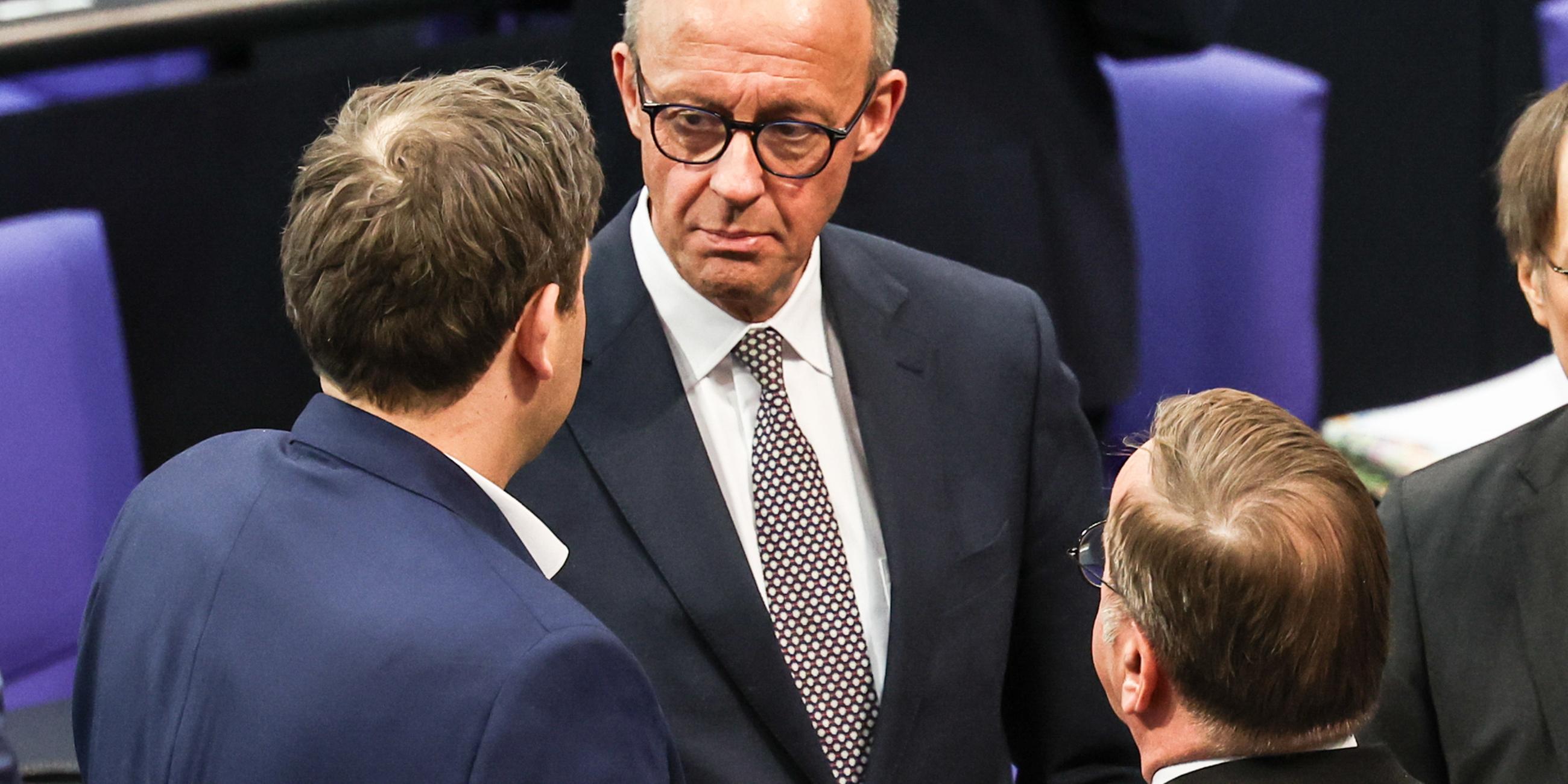 Der Partei- und Fraktionsvorsitzende der Christlich Demokratischen Union (CDU), Friedrich Merz (M.), spricht mit dem Ko-Vorsitzenden der Sozialdemokratischen Partei (SPD), Lars Klingbeil (L.), während einer Sonderplenarsitzung des Deutschen Bundestages am 18. März 2025 in Berlin. 