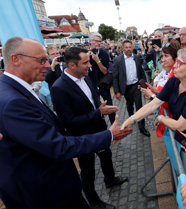 Bundeskanzler Friedrich Merz (CDU, l) und Daniel Peters, Spitzenkandidat der CDU bei den Landtagswahlen in Mecklenburg-Vorpommern, sprechen bei einer Wahlkampfveranstaltung der CDU mit Menschen.