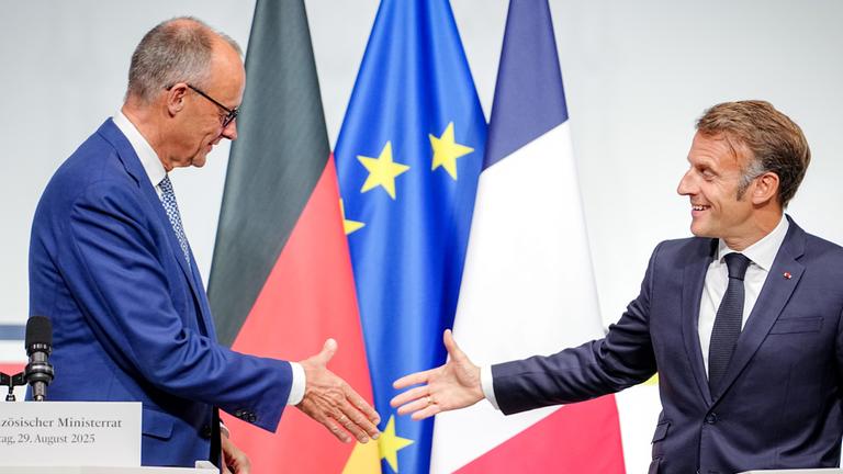  Bundeskanzler Friedrich Merz (CDU, l) und Frankreichs Präsident Emmanuel Macron reichen sich beim deutsch-französischen Regierungstreffen zur Wirtschafts- und Sicherheitspolitik nach der Pressekonferenz die Hände.
