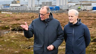 Bundeskanzler Friedrich Merz (l, CDU) und Jonas Gahr Støre, Ministerpräsident von Norwegen, unterhalten sich vor der Kulisse der Raketenstartrampe