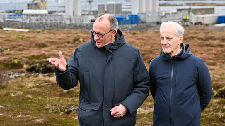 Bundeskanzler Friedrich Merz (l, CDU) und Jonas Gahr Støre, Ministerpräsident von Norwegen, unterhalten sich vor der Kulisse der Raketenstartrampe