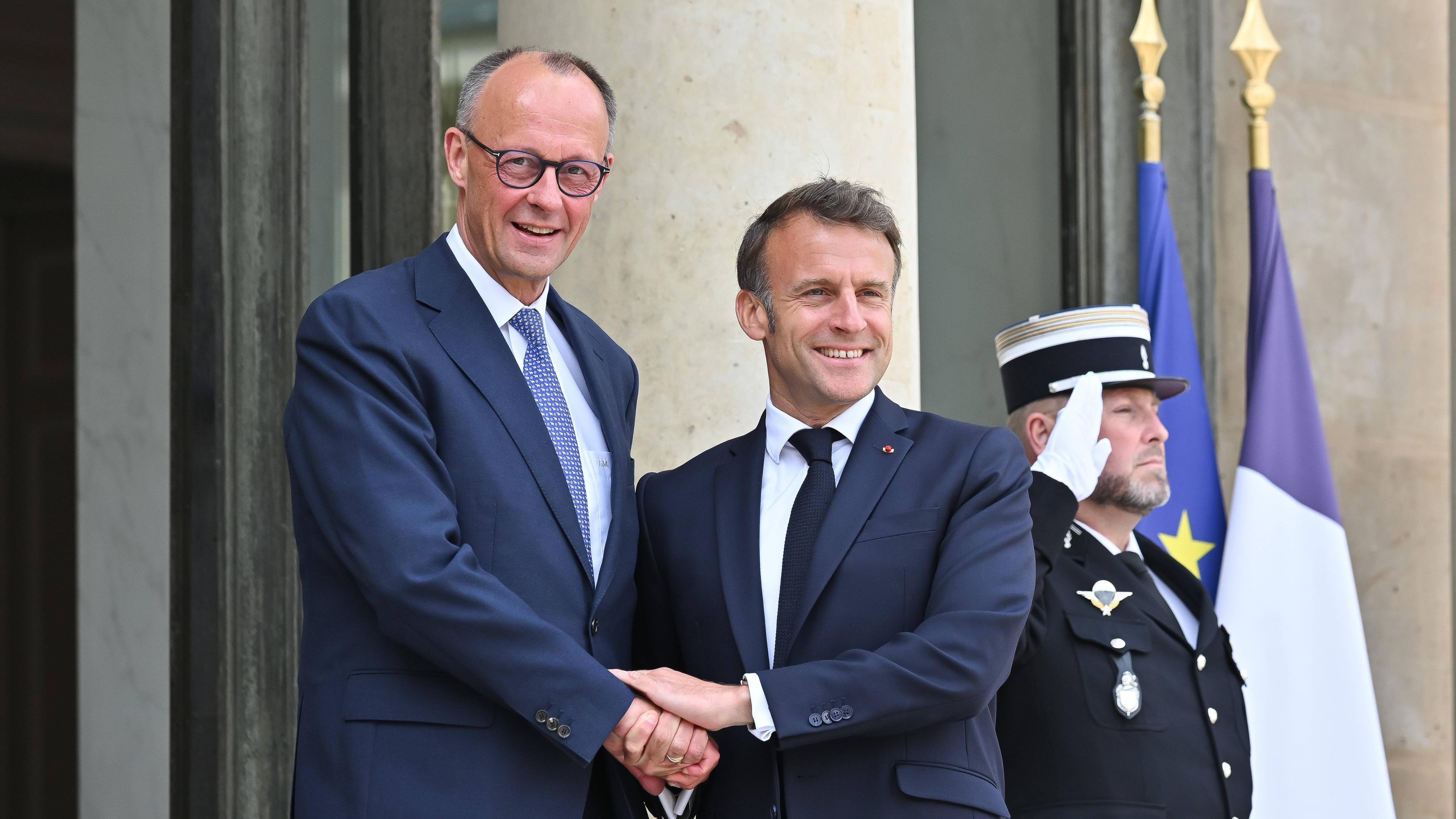 Der französische Präsident Emmanuel Macron schüttelt Bundeskanzler Friedrich Merz vor dem Élysée-Palast in Paris die Hand.