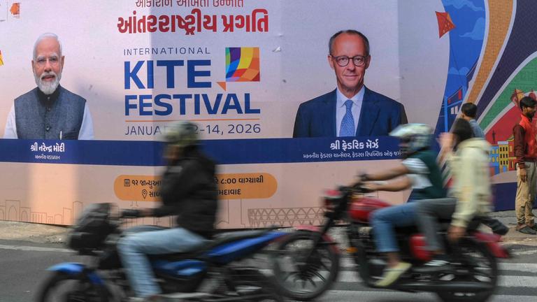 Motorradfahrer passieren in Ahmedabad am 8. Januar 2026 eine Werbetafel mit Fotos von Deutschlands Bundeskanzler Friedrich Merz (r.) und Indiens Premierminister Narendra Modi anlässlich des bevorstehenden Indien-Besuchs von Merz.