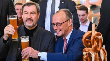 Der CDU-Vorsitzende Merz und CSU-Chef Söder trinken während einer Wahlkampfveranstaltung ein Bier.