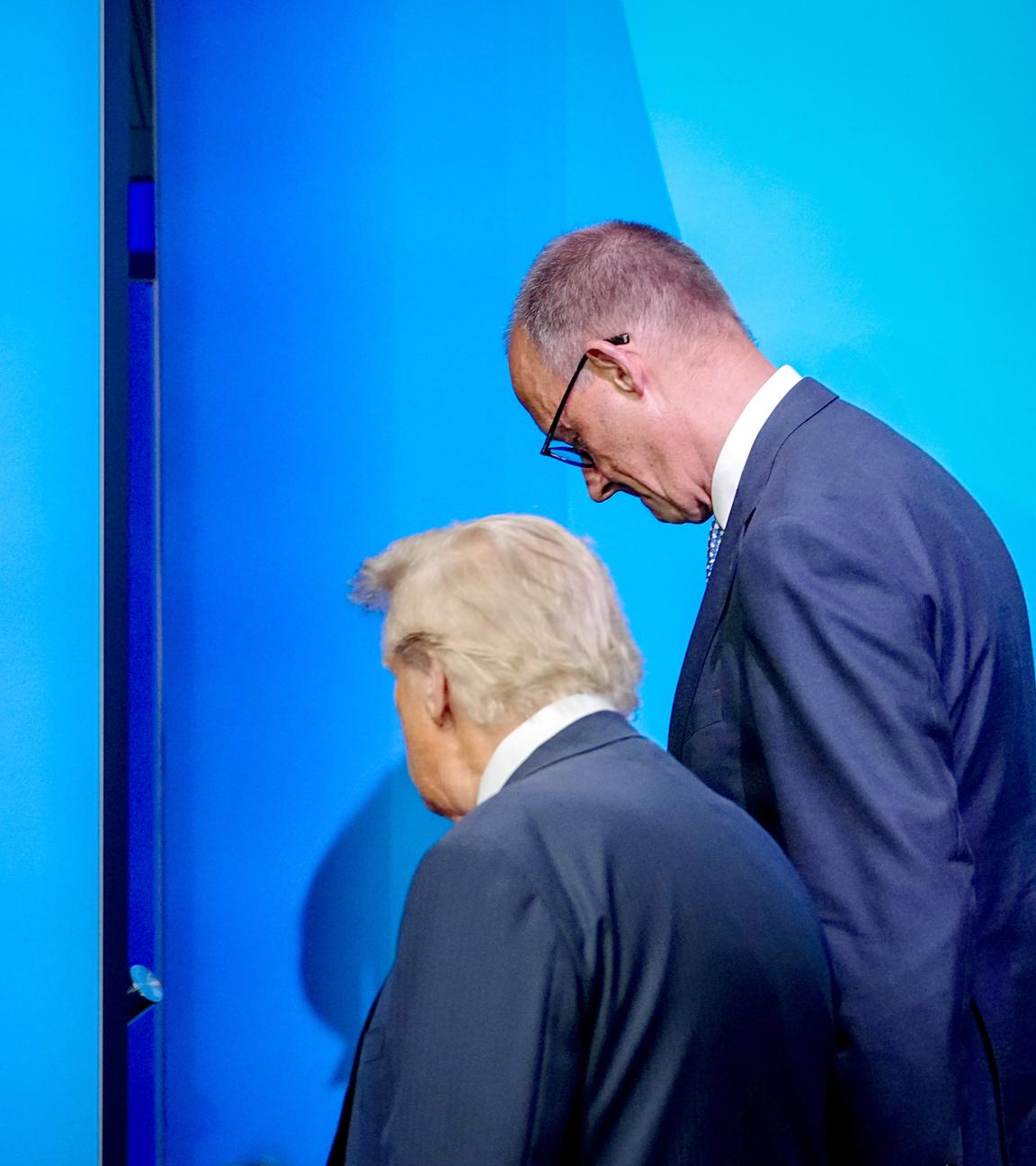 Bundeskanzler Friedrich Merz (CDU, r), und US-Präsident Donald Trump unterhalten sich beim Nato-Gipfel nach dem Familienfoto. 