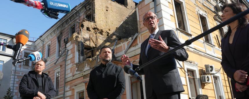 Der ukrainische Präsident Wolodymyr Selenskyj und der deutsche Bundeskanzler Friedrich Merz geben vor einem durch eine russische Drohne zerstörten Haus ein Pressestatement ab.