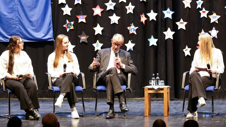 Bundeskanzler Friedrich Merz (Mitte) unterhält sich bei seinem Besuch am Carolus-Magnus-Gymnasium anlässlich des EU-Projekttags 2026 an Schulen in Marsberg mit Schülern.