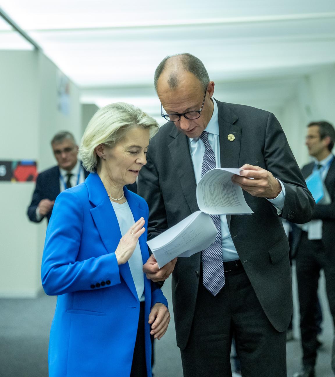 Bundeskanzler Friedrich Merz (CDU, e) spricht mit Ursula von der Leyen, Präsidentin der EU-Kommission, beim G20-Gipfel auf dem Weg zum Familienfoto. 
