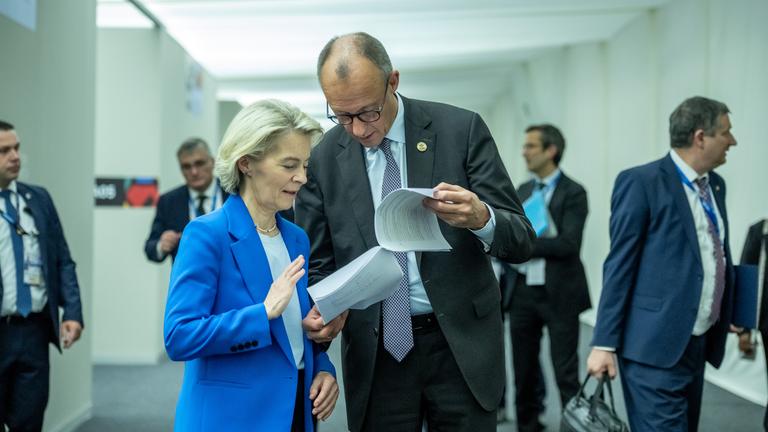Bundeskanzler Friedrich Merz (CDU, e) spricht mit Ursula von der Leyen, Präsidentin der EU-Kommission, beim G20-Gipfel auf dem Weg zum Familienfoto. 