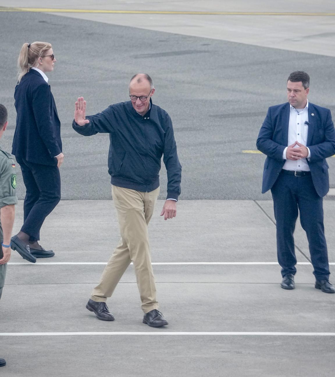 Merz kommt am Flughafen an und winkt