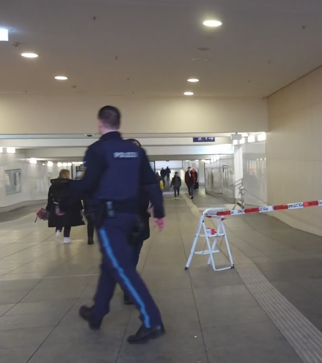 Drei Polizisten in einer Unterführung am Hauptbahnhof Würzburg. Ein Absperrband ist an einer Tretleiter befestigt.