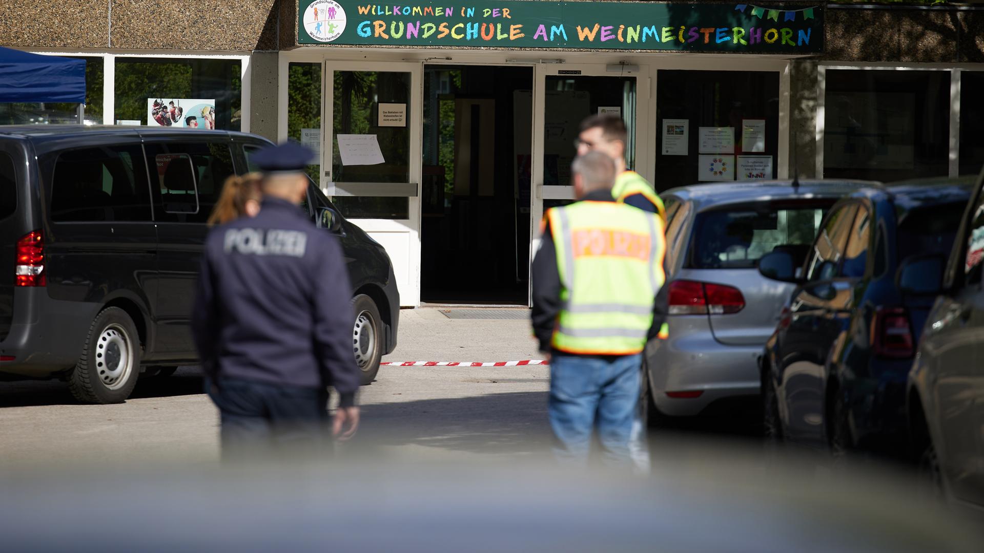 22.05.2025, Berlin: Polizisten stehen vor einer Schule im Berliner Bezirk Spandau, an der es am Vormittag einen möglichen Messerangriff auf einen Schüler gab.
