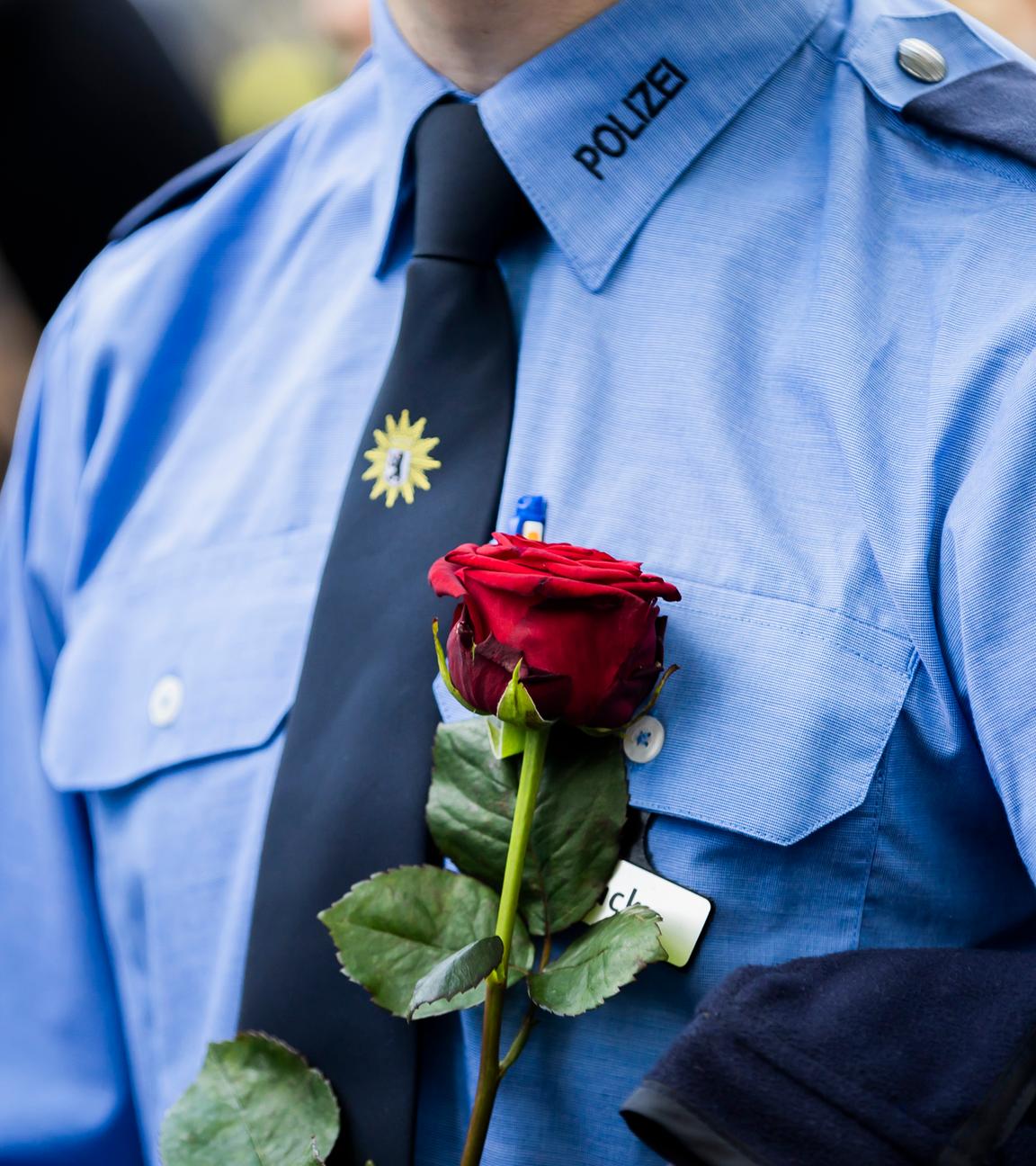 Ein Polizist hält bei einem Gedenken am Ende eines Schweigemarschs der «Blaulichtfamilie» von der Deutschen Polizeigewerkschaft (DPolG) und der Gewerkschaft der Polizei (GdP) an der Landesvertretung von Baden-Württemberg für den durch einen Messerangriff in Mannheim zu Tode gekommenen Polizisten eine Rose. 