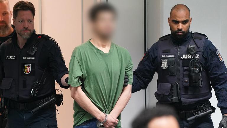 Der Angeklagte Ibrahim A. (M) wird in Handschellen in den Gerichtssaal im China Logistic Center gebracht, aufgenommen am 02.05.2024 in Itzehoe