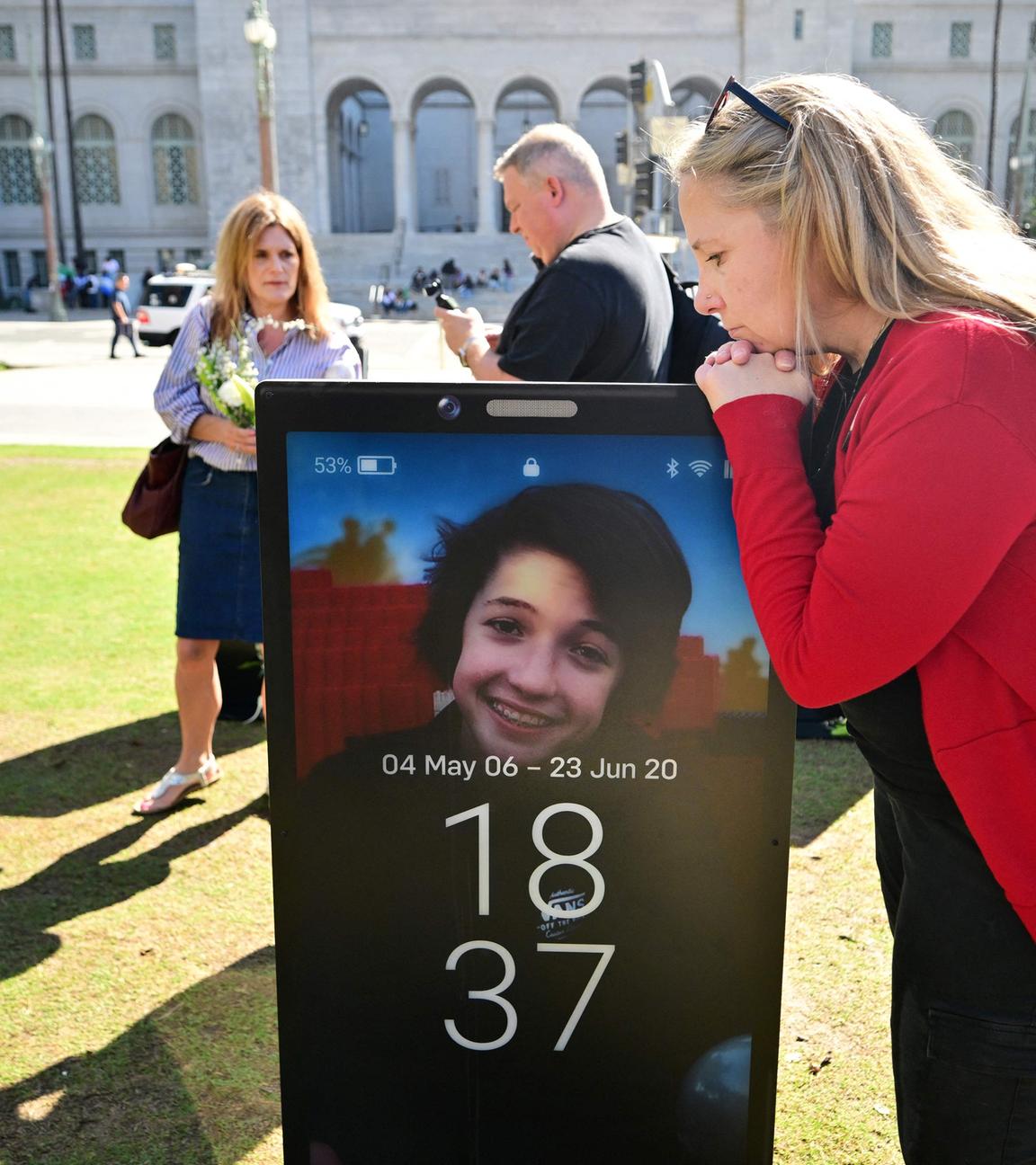 Trauernde Eltern betrachten Bilder ihrer verstorbenen Kinder, die aufgrund von Online-Gefahren ihr Leben verloren habend und nun auf dem „Lost Screen Memorial“ ausgestellt sind.