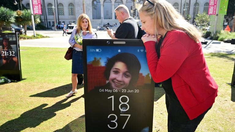 Trauernde Eltern betrachten Bilder ihrer verstorbenen Kinder, die aufgrund von Online-Gefahren ihr Leben verloren habend und nun auf dem „Lost Screen Memorial“ ausgestellt sind.