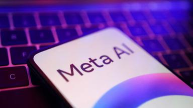Ein Smartphone liegt auf einer Computertastatur, auf dem Smartphonebildschirm wird "Meta AI" angezeigt.