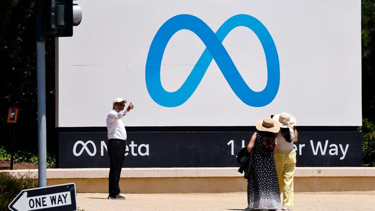 Eine Person posiert mit erhobenem Daumen neben der Meta-Beschilderung vor dem Hauptsitz von Meta Platforms (Meta) in Menlo Park, Kalifornien