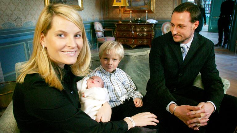 Mette-Marit, Haakon und Marius lächeln mit Baby Ingrid Alexandra auf dem Arm.