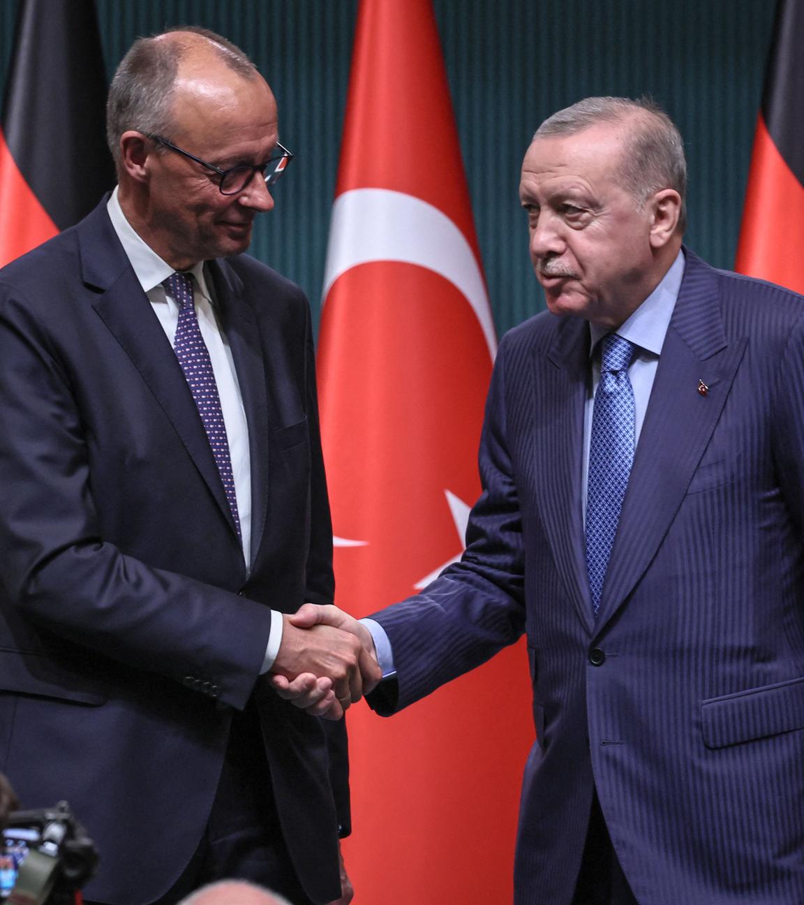 Turkey's President Recep Tayyip Erdogan (R) shakes hands with German Chancellor Friedrich Merz.