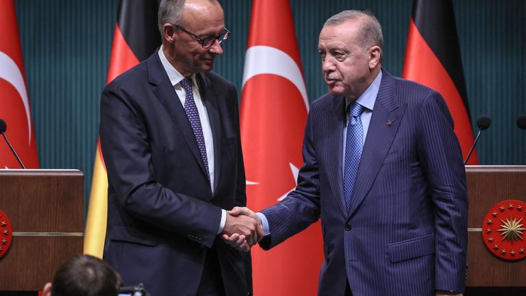Turkey's President Recep Tayyip Erdogan (R) shakes hands with German Chancellor Friedrich Merz.