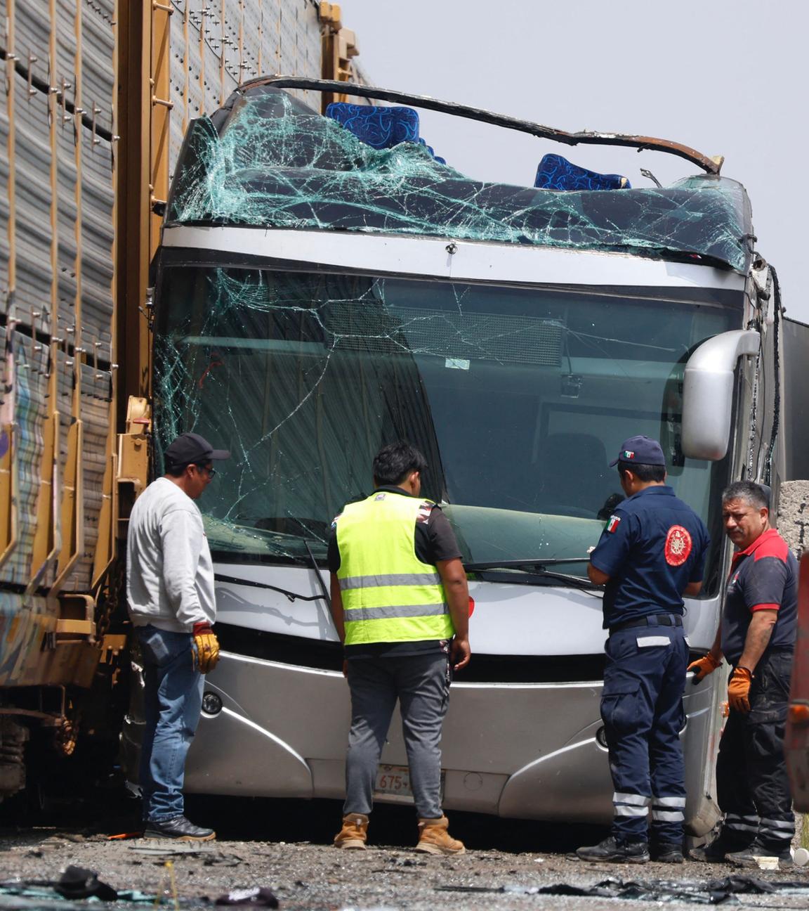 Rescue workers stand next to the wreckage of a passenger bus involved in an accident with a train
