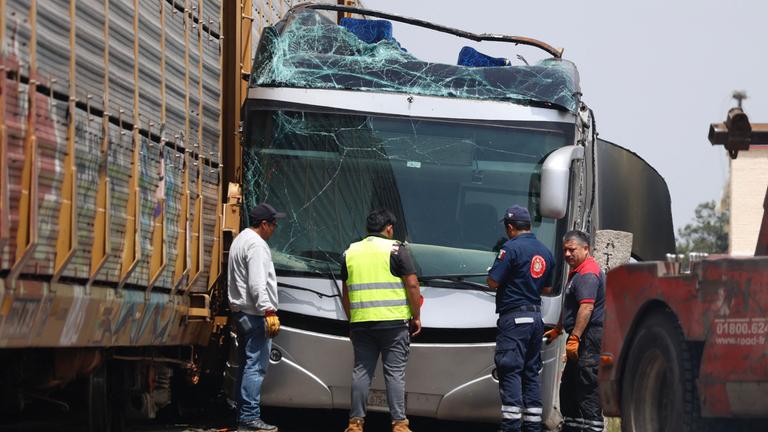 Rescue workers stand next to the wreckage of a passenger bus involved in an accident with a train