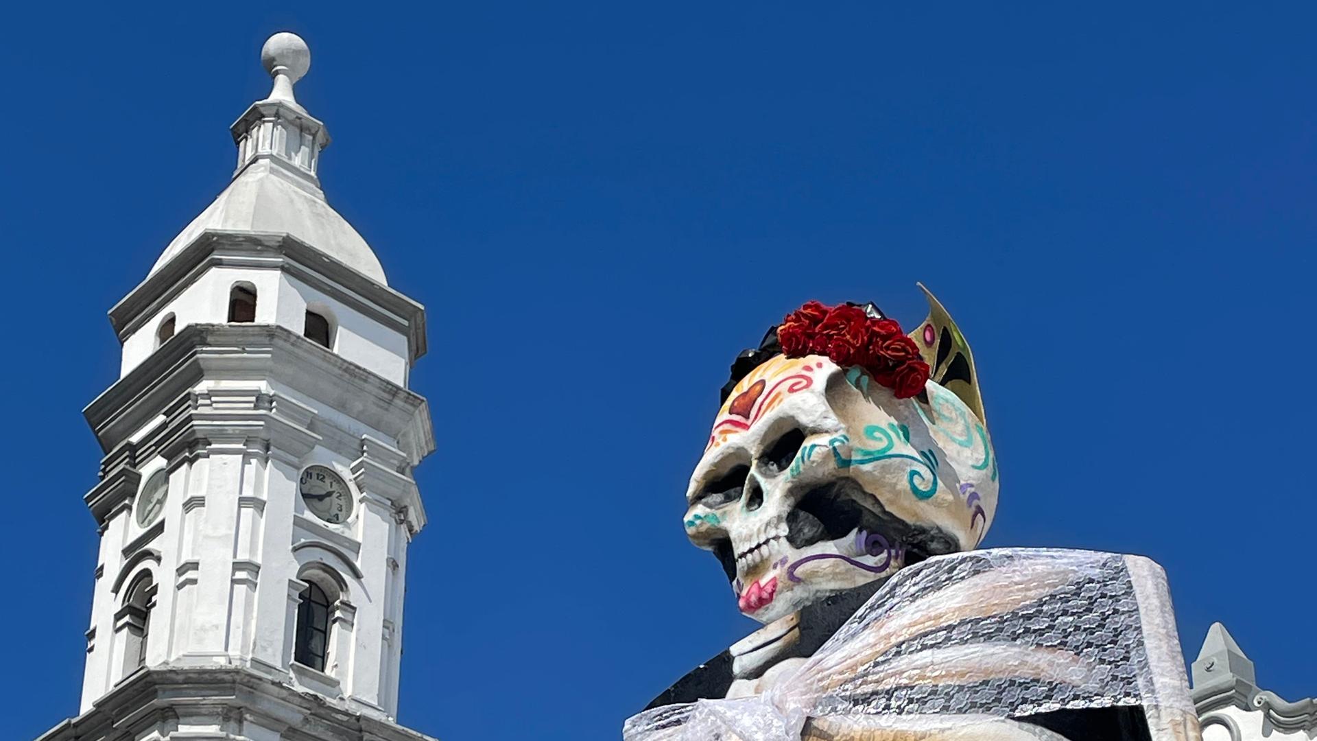 In einer Stadt ist eine meterhohe Skelettfrau zu sehen.