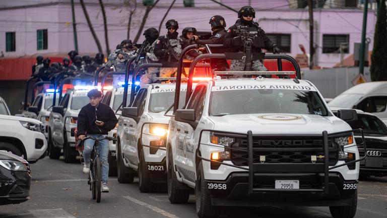 Einsatzwagen der Spezialeinheiten der Nationalgarde und der Secretaria de Seguridad Ciudadana stehen hintereinander. Bewaffnete Einsatzkräfte auf den Ladeflächen/Dächern der Autos.