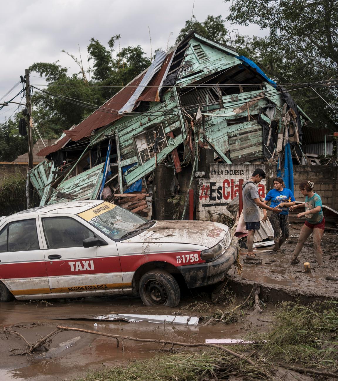 Nachbarn versammeln sich nach heftigen Regenfällen um ein beschädigtes Haus in Poza Rica, Bundesstaat Veracruz, Mexiko.